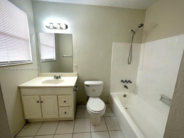 full bathroom with tile patterned flooring, vanity, tiled shower / bath combo, and toilet