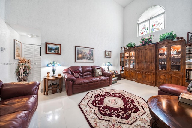 living room with a towering ceiling and light tile patterned floors