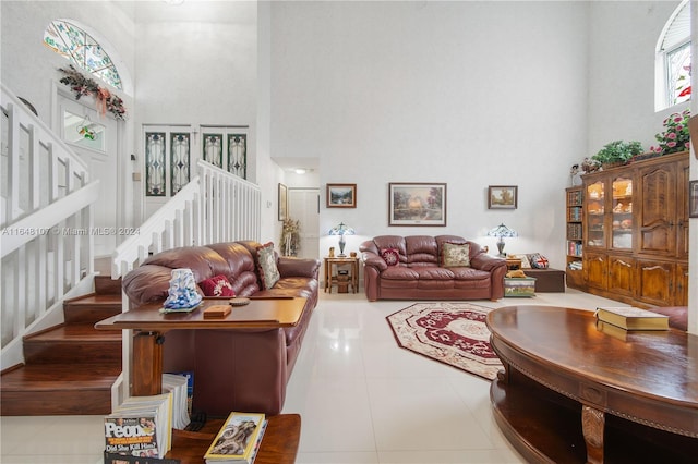 living room featuring light tile patterned floors, a towering ceiling, and stairs