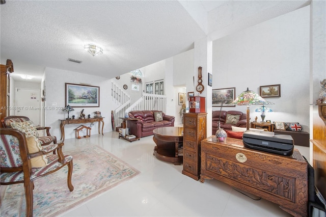 living area featuring a textured ceiling, stairway, tile patterned flooring, and visible vents