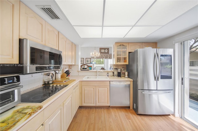 kitchen with a sink, visible vents, light countertops, appliances with stainless steel finishes, and glass insert cabinets