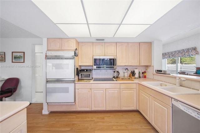 kitchen featuring light brown cabinets, a sink, light countertops, appliances with stainless steel finishes, and light wood finished floors