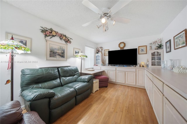 living area with a textured ceiling, ceiling fan, and light wood-style flooring