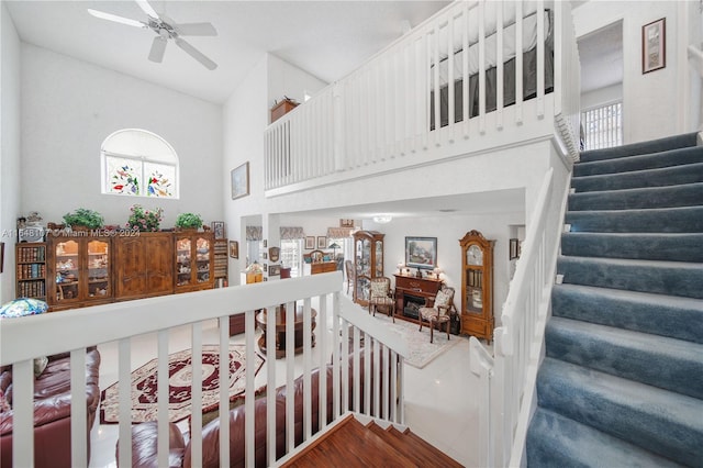 stairway with plenty of natural light, a high ceiling, and a ceiling fan