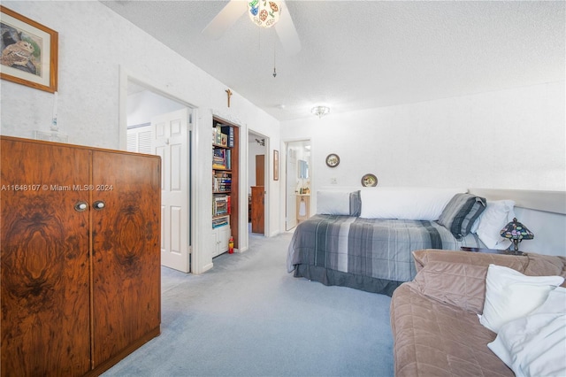 bedroom with light carpet, a ceiling fan, and a textured ceiling