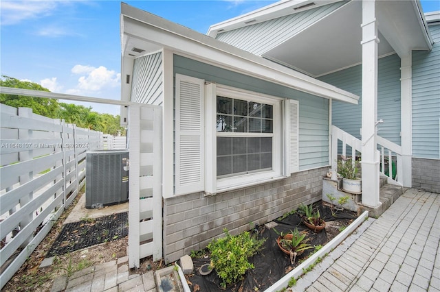 view of home's exterior featuring brick siding, cooling unit, and fence