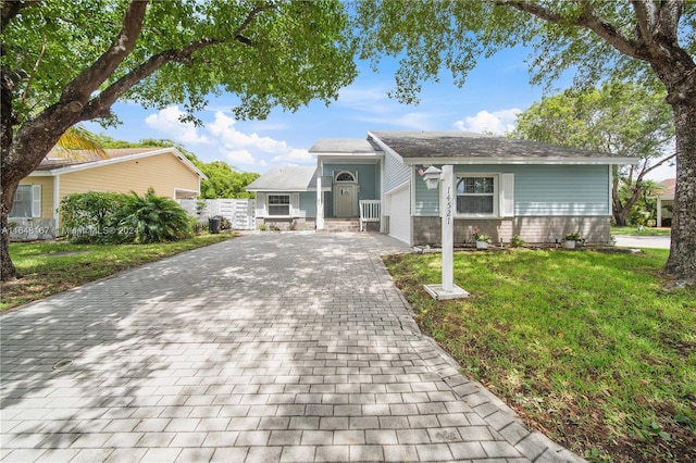 single story home featuring a front lawn and decorative driveway