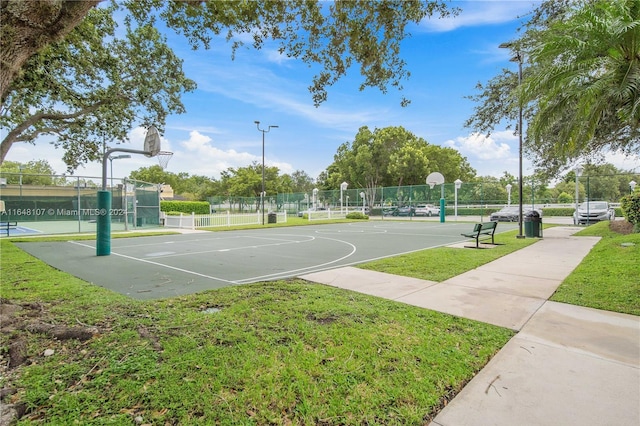 view of basketball court featuring community basketball court, fence, and a lawn