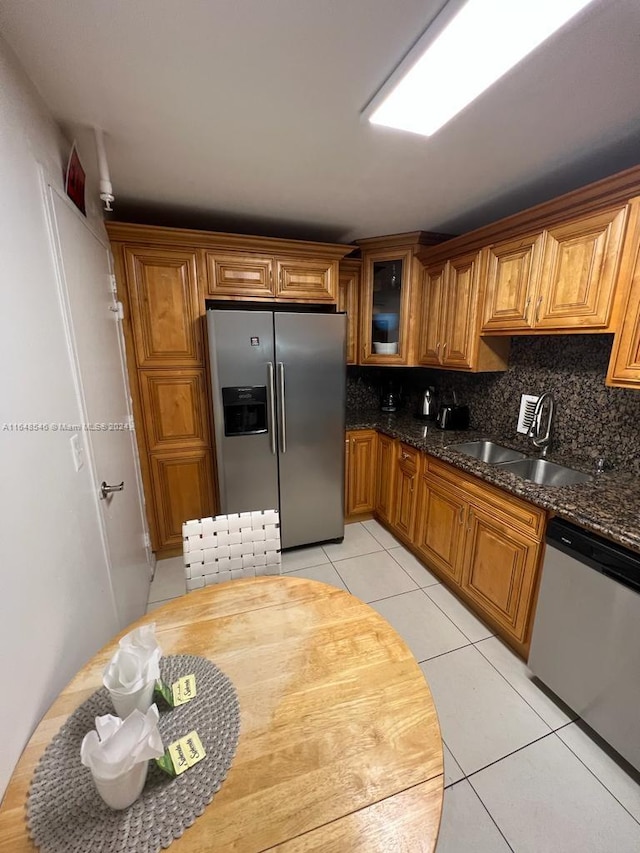 kitchen with stainless steel appliances, tasteful backsplash, sink, light tile patterned floors, and dark stone counters