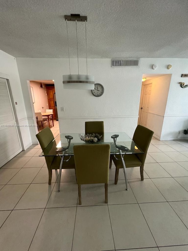 dining space featuring a textured ceiling and light tile patterned floors