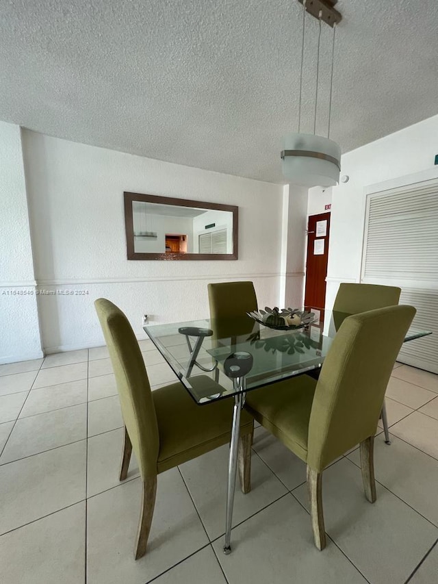 dining space featuring a textured ceiling and light tile patterned flooring