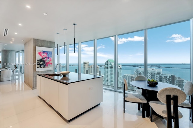 kitchen featuring sink, white cabinets, hanging light fixtures, and a wall of windows