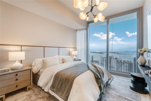 bedroom with a chandelier, a water view, and expansive windows