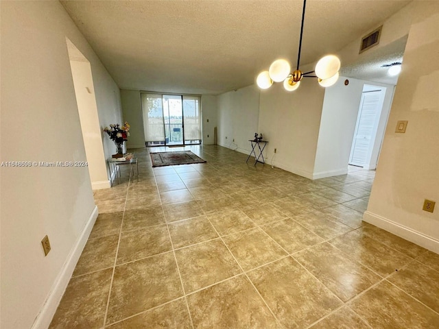 unfurnished room with light tile patterned flooring, a notable chandelier, and a textured ceiling