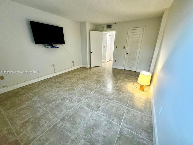 tiled spare room with a textured ceiling