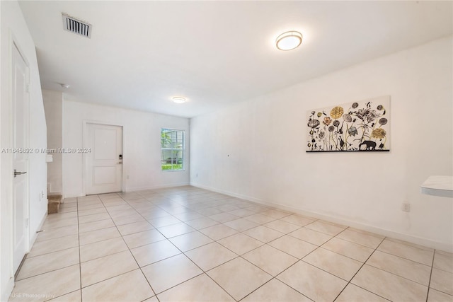 empty room with light tile patterned flooring, visible vents, and baseboards