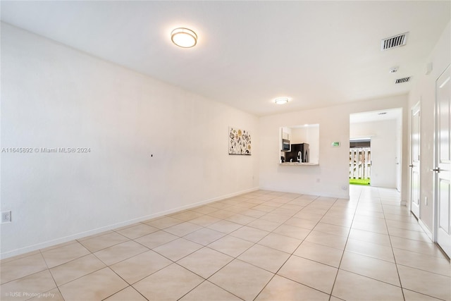 spare room featuring light tile patterned flooring, visible vents, and baseboards