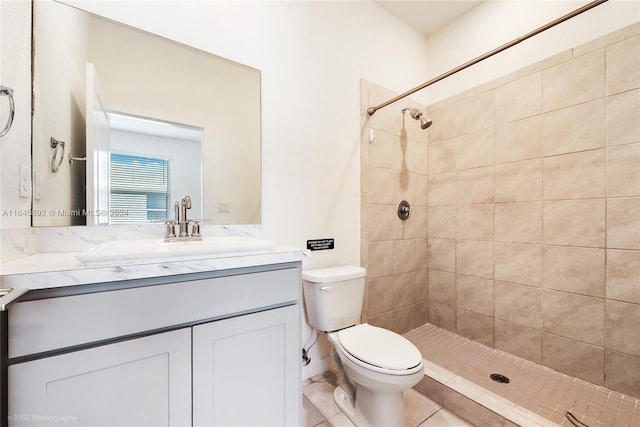 bathroom featuring tiled shower, tile patterned flooring, vanity, and toilet