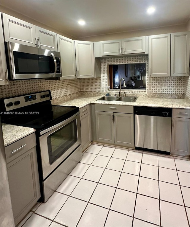 kitchen with sink, decorative backsplash, light tile patterned floors, and stainless steel appliances