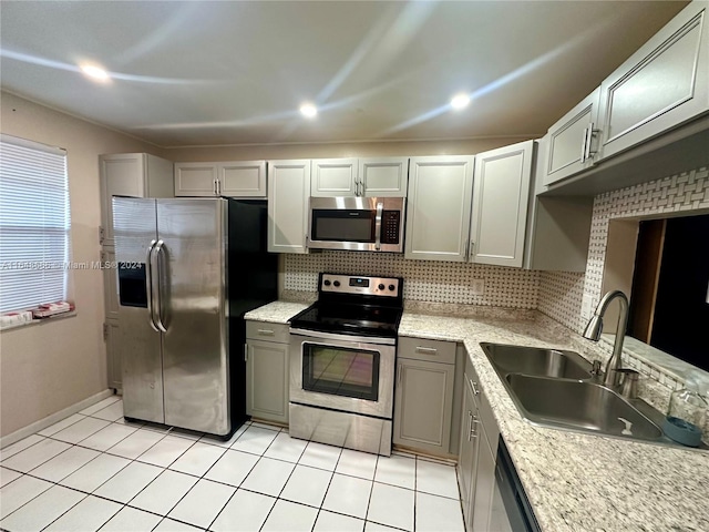 kitchen with sink, appliances with stainless steel finishes, decorative backsplash, light tile patterned floors, and gray cabinets