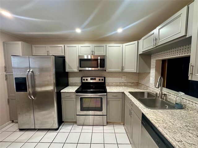 kitchen with decorative backsplash, gray cabinetry, appliances with stainless steel finishes, sink, and light tile patterned flooring