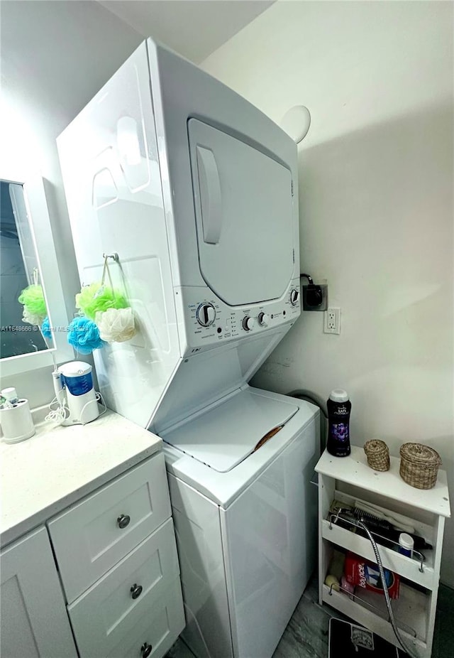 laundry room with cabinets and stacked washer and clothes dryer