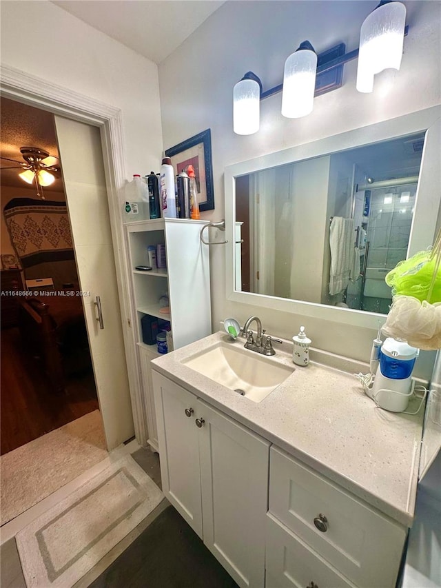 bathroom featuring ceiling fan, hardwood / wood-style floors, vanity, and walk in shower