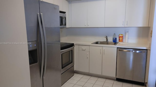 kitchen with light tile patterned flooring, appliances with stainless steel finishes, sink, and white cabinets