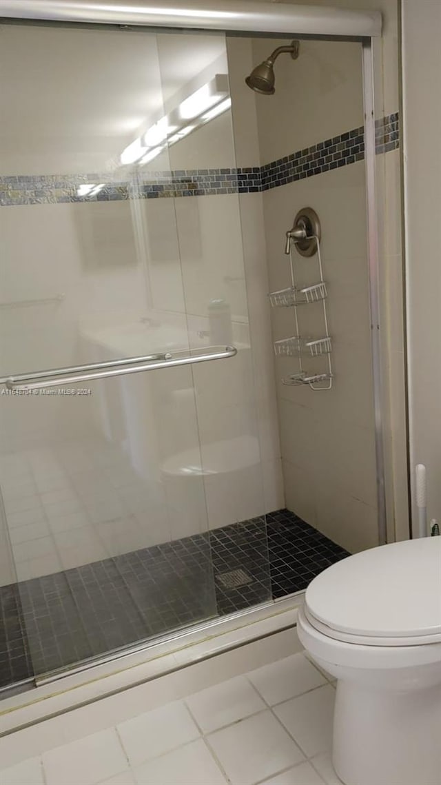 bathroom with toilet, tile patterned flooring, and a shower with door