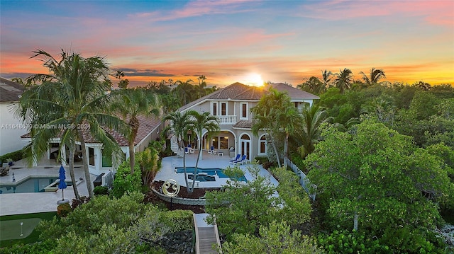 view of front of home featuring a tile roof, a fenced backyard, an outdoor pool, a balcony, and a patio area