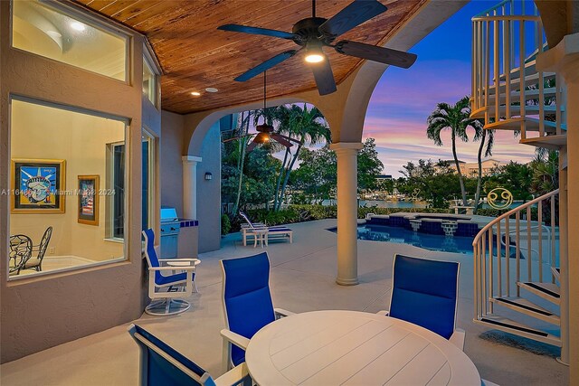 patio terrace at dusk featuring ceiling fan and a swimming pool with hot tub