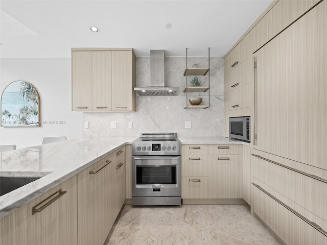 kitchen with kitchen peninsula, wall chimney exhaust hood, stainless steel appliances, light stone countertops, and light brown cabinetry