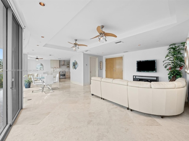 living room featuring ceiling fan and a raised ceiling