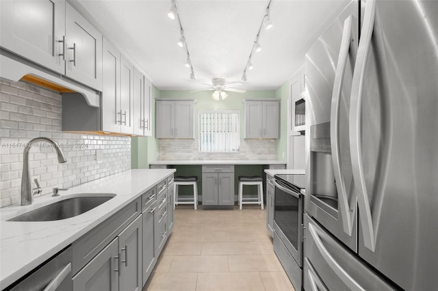 kitchen with appliances with stainless steel finishes, backsplash, rail lighting, sink, and ceiling fan