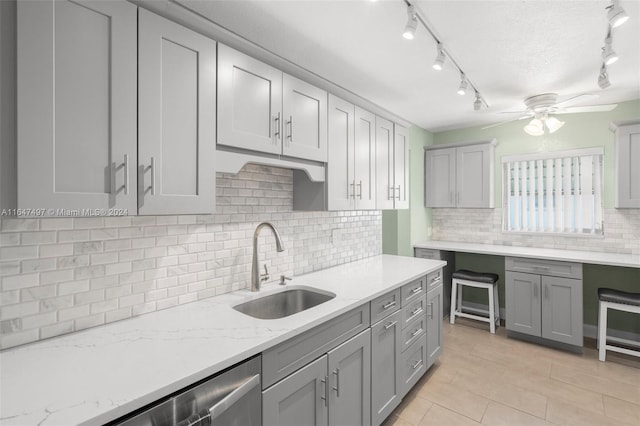 kitchen with ceiling fan, decorative backsplash, sink, rail lighting, and light tile patterned flooring