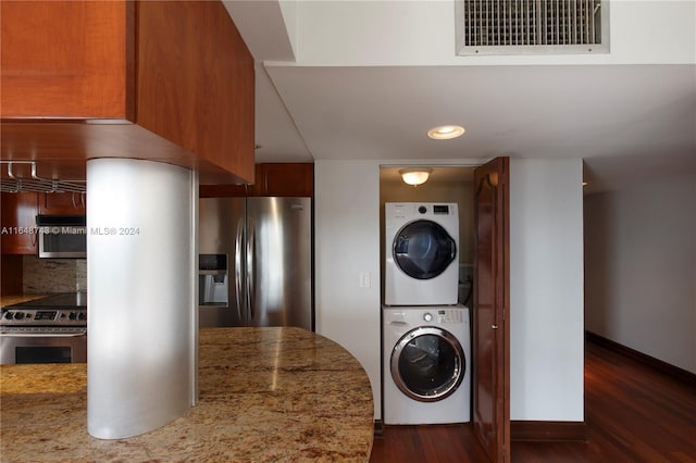 washroom with stacked washer and dryer and dark hardwood / wood-style flooring