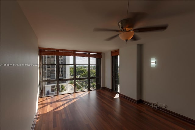 spare room with ceiling fan, hardwood / wood-style flooring, and a wall of windows