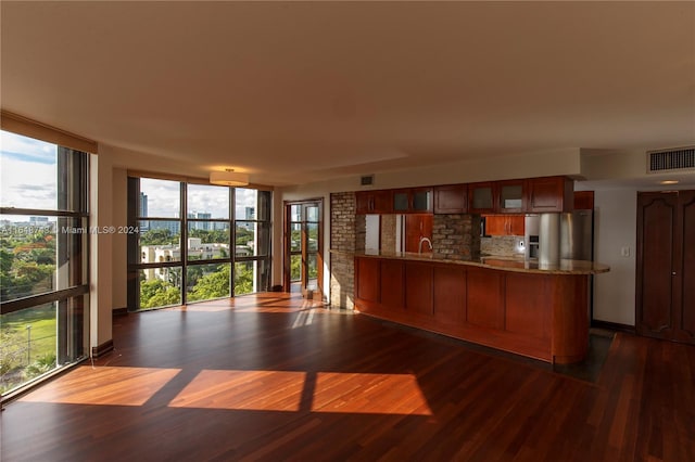 kitchen with backsplash, dark hardwood / wood-style flooring, plenty of natural light, kitchen peninsula, and stainless steel fridge