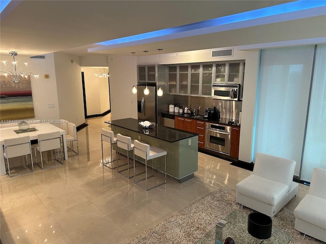 kitchen featuring a breakfast bar, a chandelier, a kitchen island, appliances with stainless steel finishes, and decorative light fixtures