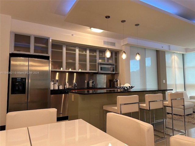 kitchen featuring a breakfast bar area, stainless steel appliances, and decorative light fixtures