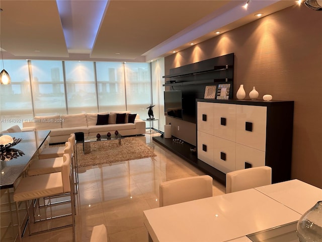 kitchen with a center island, light tile patterned flooring, floor to ceiling windows, white cabinetry, and decorative light fixtures