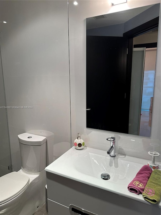 bathroom featuring tile walls, vanity, and toilet