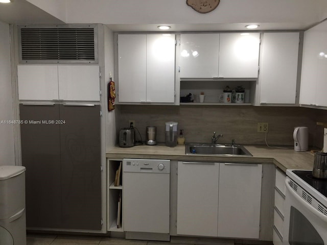 kitchen featuring light tile patterned floors, sink, decorative backsplash, white appliances, and white cabinetry