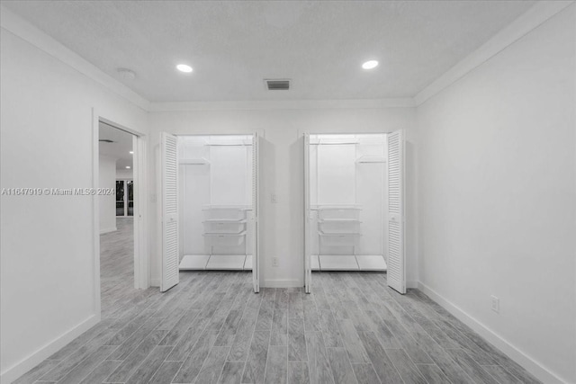 unfurnished bedroom featuring ornamental molding, a textured ceiling, and light wood-type flooring