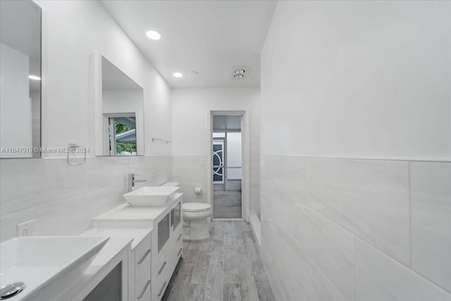 bathroom with vanity, toilet, tile walls, and hardwood / wood-style floors