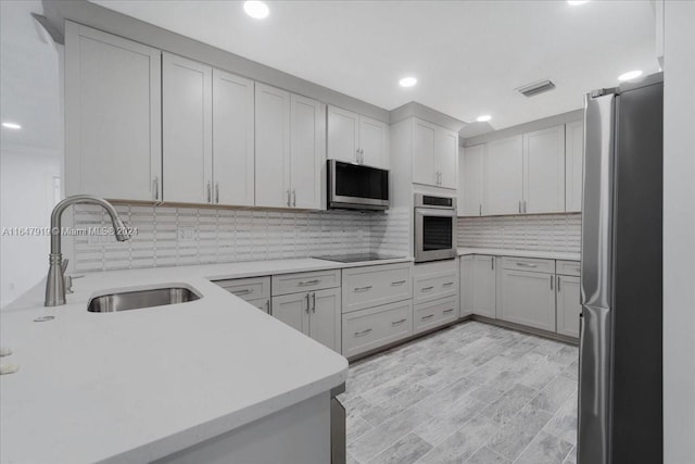 kitchen featuring tasteful backsplash, appliances with stainless steel finishes, sink, and light wood-type flooring