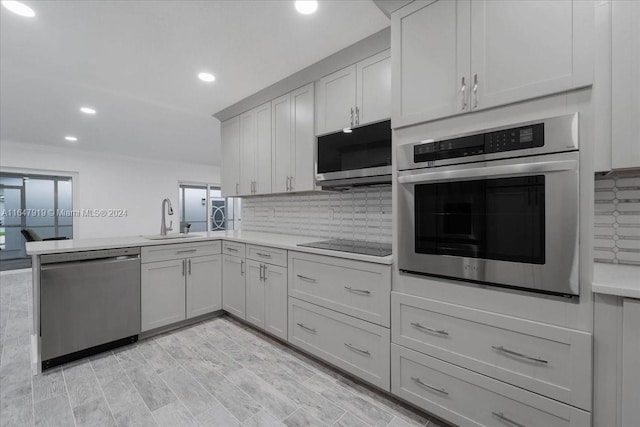 kitchen with kitchen peninsula, tasteful backsplash, appliances with stainless steel finishes, light hardwood / wood-style flooring, and sink