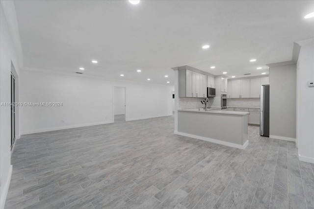 kitchen with backsplash, white cabinets, kitchen peninsula, and light wood-type flooring