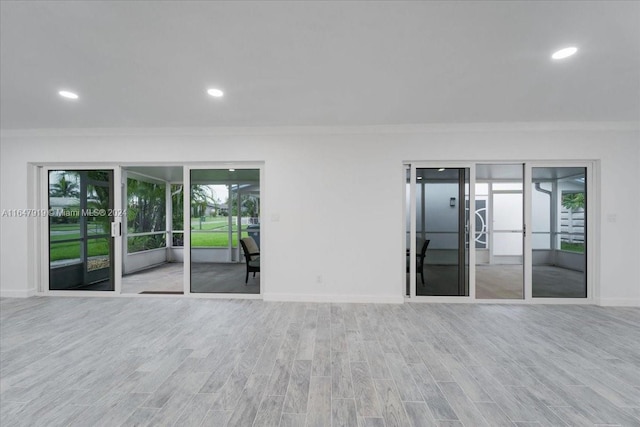 empty room with light hardwood / wood-style floors and crown molding