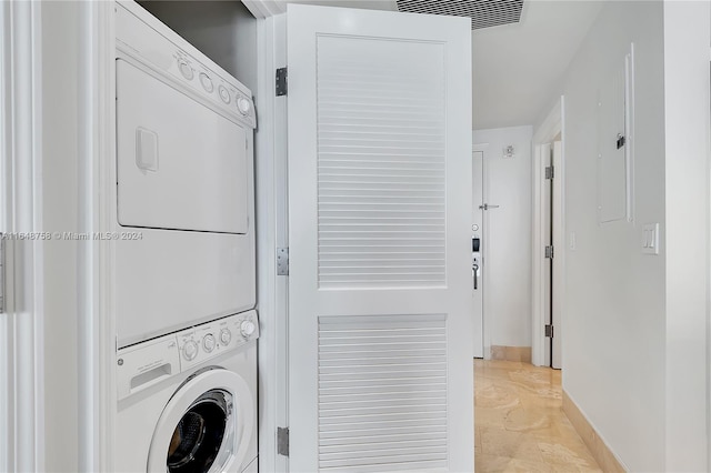 washroom with stacked washing maching and dryer and light tile patterned floors